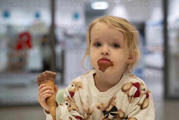 Interior shot, girl, 2-3 years, blonde, eating chocolate ice cream, ice cream, waffle, mouth smeared, logo pharmacy, Stuttgart, Baden-Wuerttemberg, Germany, Europe