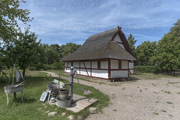 Thatched half-timbered barn, in front a water pump with washing tubs from the 19th century, open-air museum for folklore Schwerin-Muess, Mecklenburg-Vorpommerm, Germany, Europe