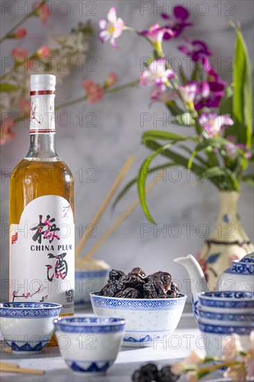 Asian tea set with blue patterns, a bottle of Chinese plum wine and dried fruit