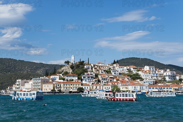 View of a picturesque harbour with colourful houses and boats against a blue sky with clouds, view from Galatas, Argolis, to Poros, Poros Island, Saronic Islands, Peloponnese, Greece, Europe