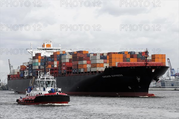 A large container ship loaded with colourful containers escorted by a tugboat, Hamburg, Hanseatic City of Hamburg, Germany, Europe