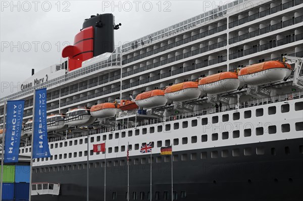 The Queen Mary 2 in the harbour with lifeboats and advertising banners, Hamburg, Hanseatic City of Hamburg, Germany, Europe