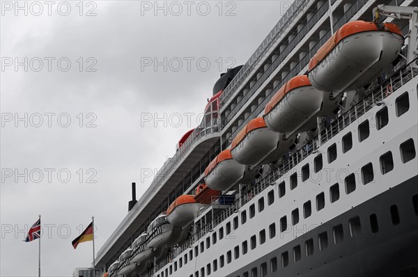 Side view of a cruise ship Queen Mary 2, with lined up lifeboats and flags, Hamburg, Hanseatic City of Hamburg, Germany, Europe