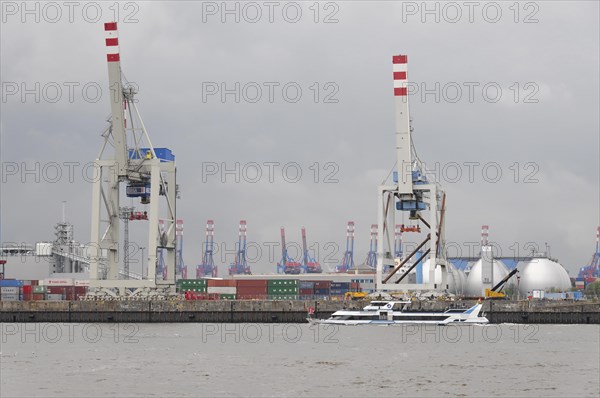 A small boat sails in front of a harbour with large cranes under a cloudy sky, Hamburg, Hanseatic City of Hamburg, Germany, Europe