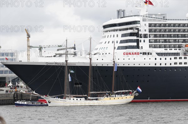 A small sailing boat next to the giant cruise ship Queen Mary 2, Hamburg, Hanseatic City of Hamburg, Germany, Europe