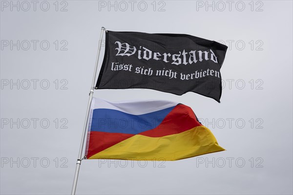A waving flag with the inscription 'AeoeWiderstand laesst sich nicht verbieten'Aeo and a combination of German and Russian flags, taken during the 'AeoeBauern-Proteste'Aeo in Berlin, 22 March 2024