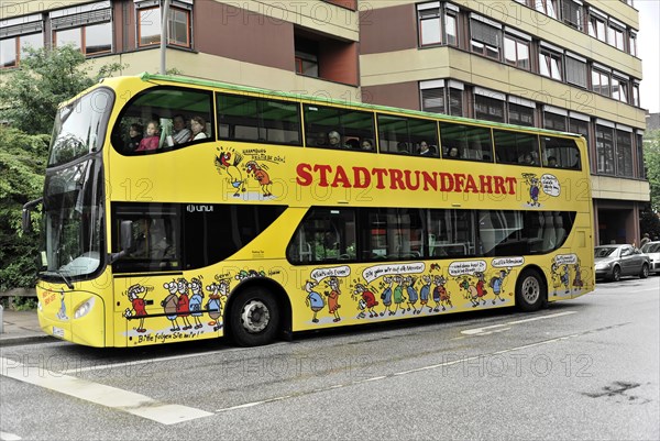 A yellow double-decker sightseeing bus with cartoon character motifs drives through the city, Hamburg, Hanseatic City of Hamburg, Germany, Europe