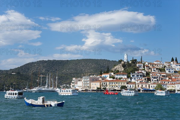 View of a picturesque coastal town with colourful boats on clear blue water under a partly cloudy sky, view from Galatas, Argolis, to Poros, Poros Island, Saronic Islands, Peloponnese, Greece, Europe