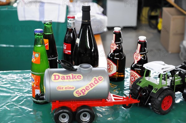 RETRO CLASSICS 2010, Stuttgart Trade Fair, Appeal for donations with a donation tin surrounded by drinks bottles and a small tractor, Stuttgart Trade Fair, Stuttgart, Baden-Wuerttemberg, Germany, Europe