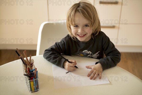 Indoor photo, boy, 4-5 years, blond, painting on sheet of paper, pencils, table, laughing, cheerful, Stuttgart, Baden-Wuerttemberg, Germany, Europe