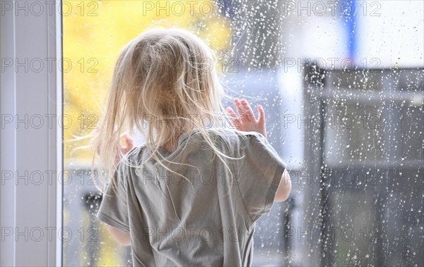 Little girl, 2-3 years, blonde, portrait, in front of window, looking at rain, raindrops on window pane, Stuttgart, Baden-Wuerttemberg, Germany, Europe