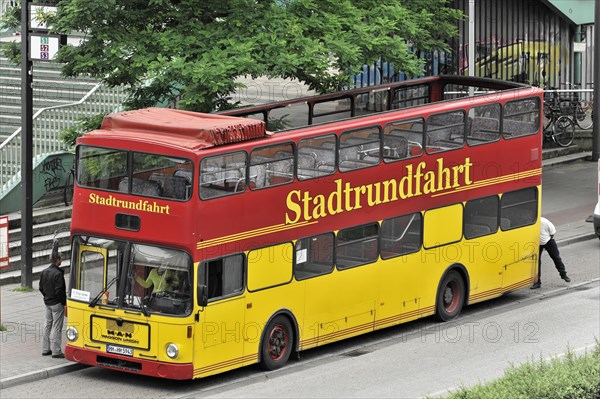 A yellow and red double-decker sightseeing bus at a bus stop with a person nearby, Hamburg, Hanseatic City of Hamburg, Germany, Europe
