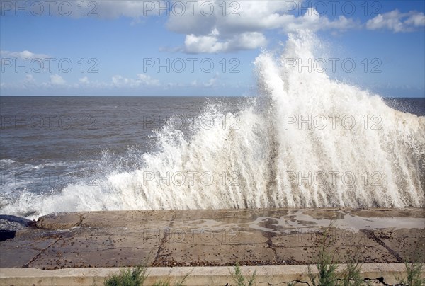 Waves hit sea wall illustrating hydraulic action and corrasion coastal erosion, East Lane, Bawdsey, Suffolk