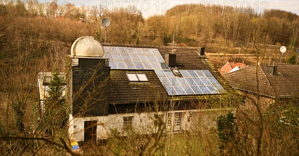 Iserlohn. Thanks to the climate change, early spring has come earlier than usual. The flowering plants in the front gardens are already showing their splendour. Residential building with observatory and older solar cell. Thanks to climate change, early spring is coming earlier than usual this year