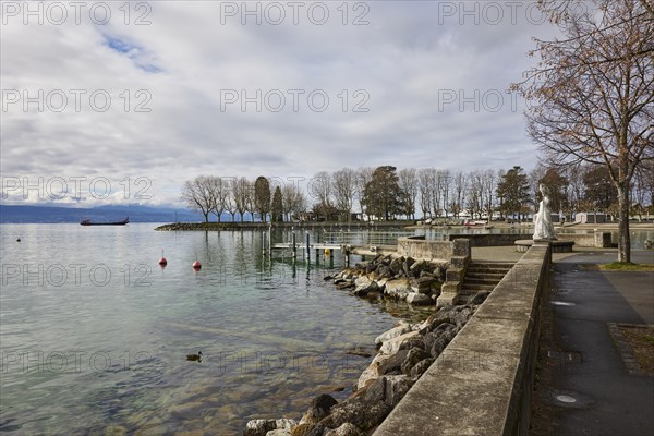 View of Lake Geneva with cargo ship from the lakeside promenade with the statue of the Virgin of Lake Geneva, Vierge du Lac in the district of Ouchy, Lausanne, district of Lausanne, Vaud, Switzerland, Europe