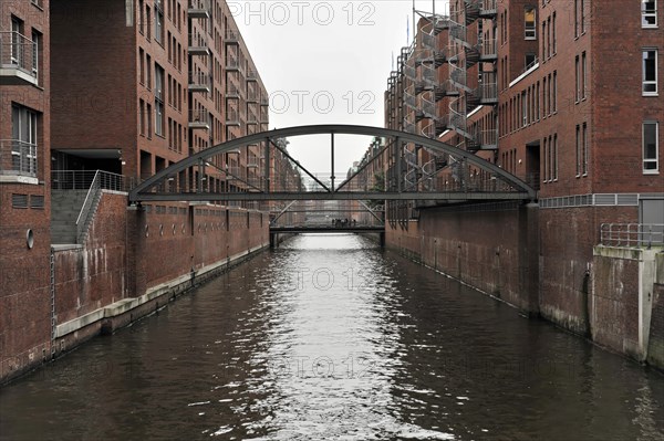 A pedestrian bridge over a water channel with brick buildings on the sides, Hamburg, Hanseatic City of Hamburg, Germany, Europe