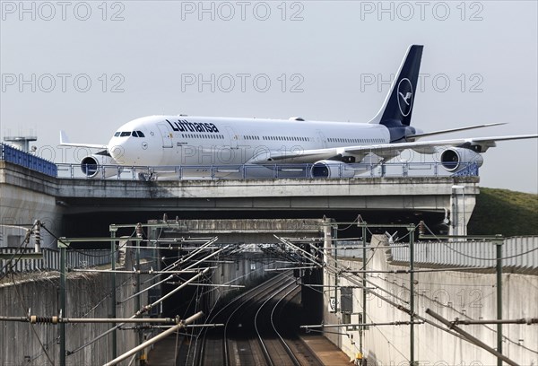 A Lufthansa Airbus A340-300 with the name of the city of Dorsten crosses a railway bridge at Frankfurt Airport, 15/03/2024