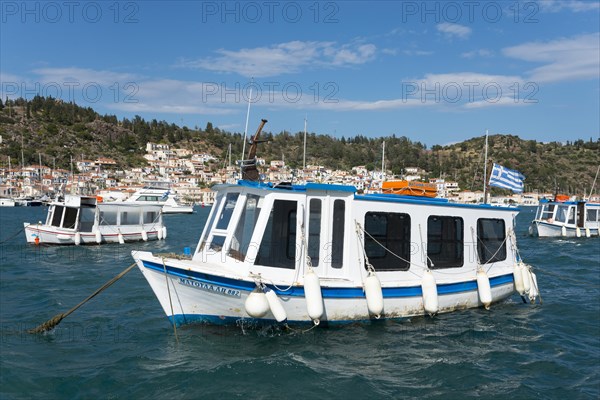 A small boat sways on the clear water of a picturesque harbour with a city view in the background, water taxi, view from Galatas, Argolis, to Poros, Poros Island, Saronic Islands, Peloponnese, Greece, Europe