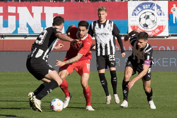 Football match, Tim KLEINDIENST 1.FC Heidenheim centre fighting for the ball with Joe SCALLY Borussia Moenchengladbach left, Robin HACK Borussia Moenchengladbach in the background and captain Julian WEIGL Borussia Moenchengladbach right, Voith-Arena football stadium, Heidenheim