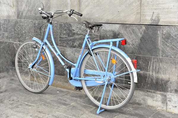 Blue bicycle leaning against a grey wall on a cobbled street, Hamburg, Hanseatic City of Hamburg, Germany, Europe