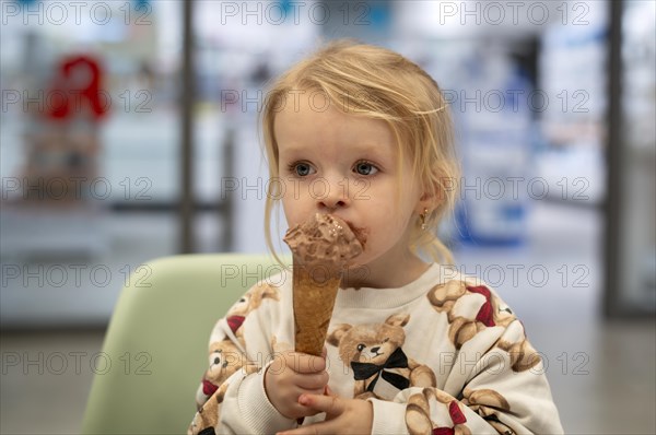 Interior shot, girl, 2-3 years, blonde, eating chocolate ice cream, ice cream, waffle, mouth smeared, logo pharmacy, Stuttgart, Baden-Wuerttemberg, Germany, Europe