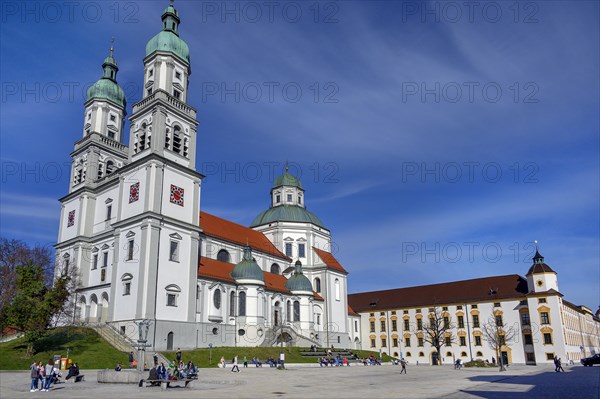 Spring awakening, people sunbathing in front of the Lorenzkirche, on the right the Residenz, Kempten, Allgaeu, Bavaria, Germany, Europe