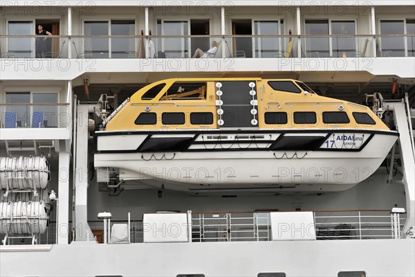 Detail, AIDALuna, A yellow lifeboat on the side of a cruise ship with people in it, Hamburg, Hanseatic City of Hamburg, Germany, Europe