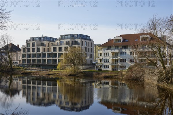 Residential and commercial buildings are reflected on the water surface of the swan pond in Minden, Muehlenkreis Minden-Luebbecke, North Rhine-Westphalia, Germany, Europe