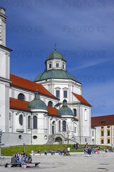 Spring awakening, people sunbathing in front of the Lorenzkirche, on the right the Residenz, Kempten, Allgaeu, Bavaria, Germany, Europe