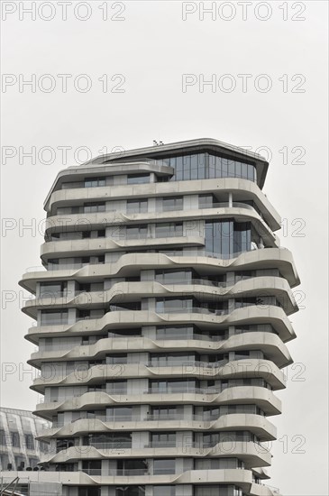 Marco Polo Tower residential tower block, Behnisch Architekten, Hafencity, Modern, curved tower block with many balconies under a cloudy sky, Hamburg, Hanseatic City of Hamburg, Germany, Europe
