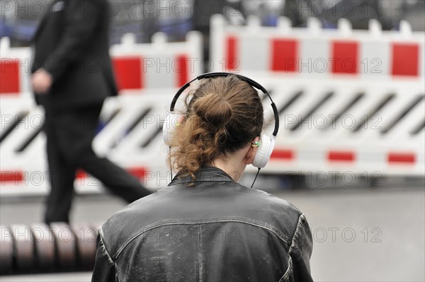 A person with headphones stands in front of a roadblock, taken from behind, Hamburg, Hanseatic City of Hamburg, Germany, Europe