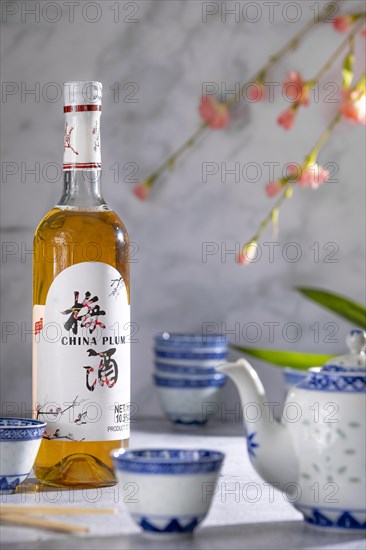 Asian tea set with blue patterns and a bottle of China plum wine