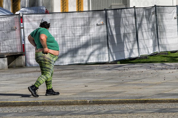 A slightly overweight young man in front of a construction fence, Bavaria, Germany, Europe