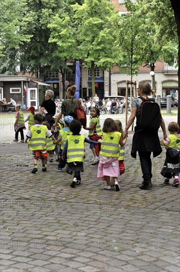 Group of children with high-visibility waistcoats on the hand of an adult in an urban environment, Hamburg, Hanseatic City of Hamburg, Germany, Europe