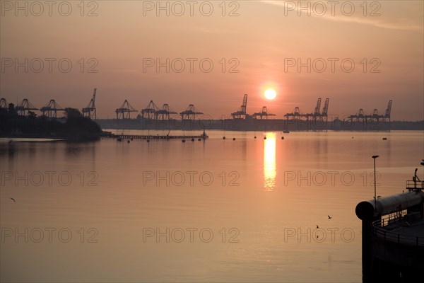 Sunrise over cranes of Port of Felixstowe, Suffolk, England viewed from Harwich
