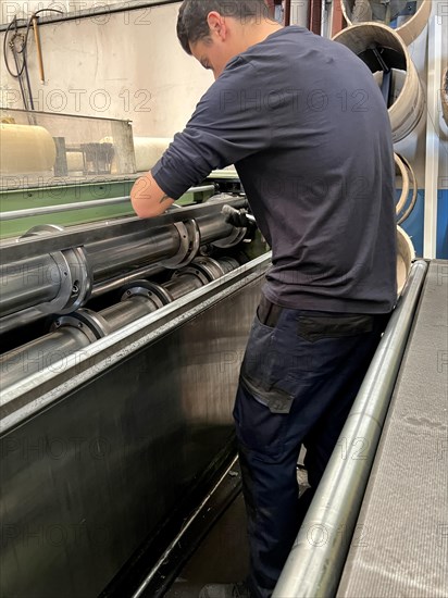 Vertical portrait of a man placing the blades for cutting sheet metal on a metal cutting machine. metalworking industry