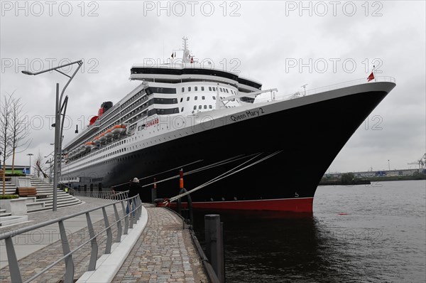 The Queen Mary 2 moored at the quay with a dramatic sky in the background, Hamburg, Hanseatic City of Hamburg, Germany, Europe