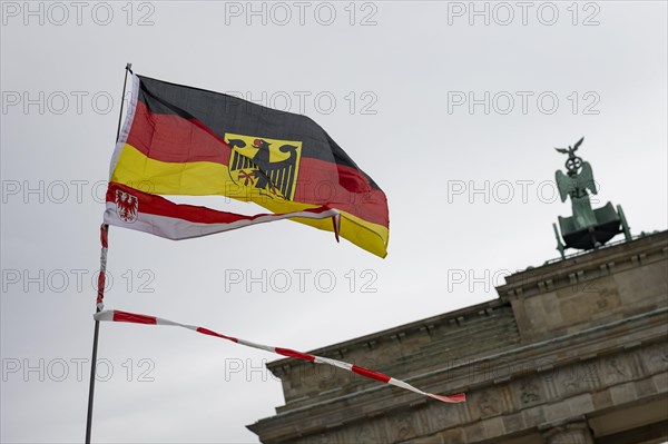 A waving German flag and Brandenburg flag with fluttering tape, the Brandenburg Gate in the background, taken as part of the 'AeoeFarmers' protests'Aeo in Berlin, 22 March 2024