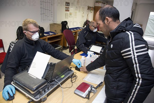Refugees are registered and recorded by the Federal Police in Rosenheim. A Federal Police officer takes a fingerprint scan, 05.02.16