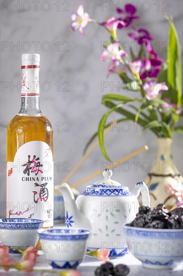 Asian tea set with blue patterns, a bottle of Chinese plum wine and dried fruit