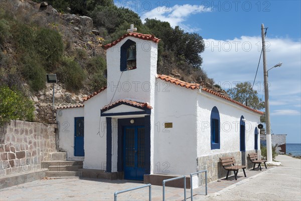 Small white chapel with blue accents located next to a quiet street, Holy Cross Church, Poros, Poros Island, Saronic Islands, Peloponnese, Greece, Europe