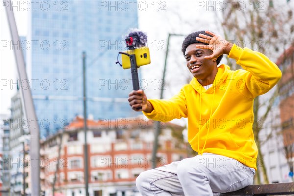 Side view photo with copy space of a young african content creator waving at camera recording a video in the city