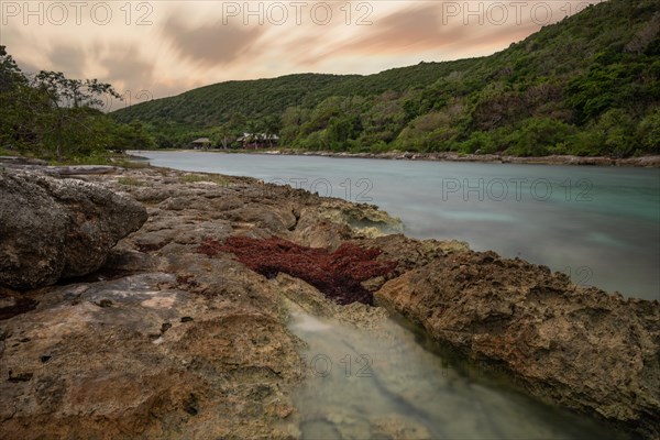 Rocky coast, long bay by the sea at sunset. Dangerous view of the Caribbean Sea. Tropical climate at sunset in La Porte d'Enfer, Grande Terre, Guadeloupe, French Antilles, North America