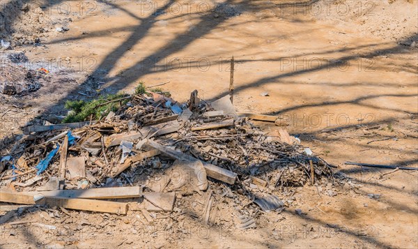 Pile of construction debris and wood scraps shadowed by a tree, in South Korea