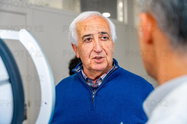 Satisfied senior man talking to an ophthalmologist in the clinic after receive an innovative glaucoma treatment with laser