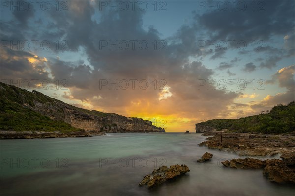 Rocky coast, long bay by the sea at sunset. Dangerous view of the Caribbean Sea. Tropical climate at sunset in La Porte d'Enfer, Grande Terre, Guadeloupe, French Antilles, North America