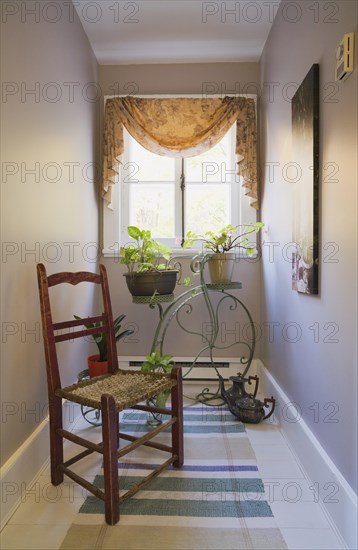 Antique wooden weaved seat chair and ornamental Penny-Farthing bicycle support stand for planters on upper floor hallway inside old 1877 home, Quebec, Canada, North America