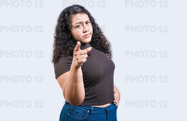 Serious young woman pointing at the camera, isolated. Young girl pointing at you frowning isolated