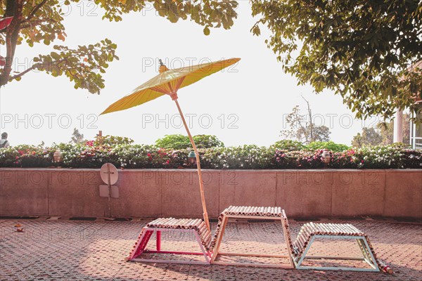 Chairs and a yellow Japanese umbrella on a summer day. Chiang rai, Thailand, Asia