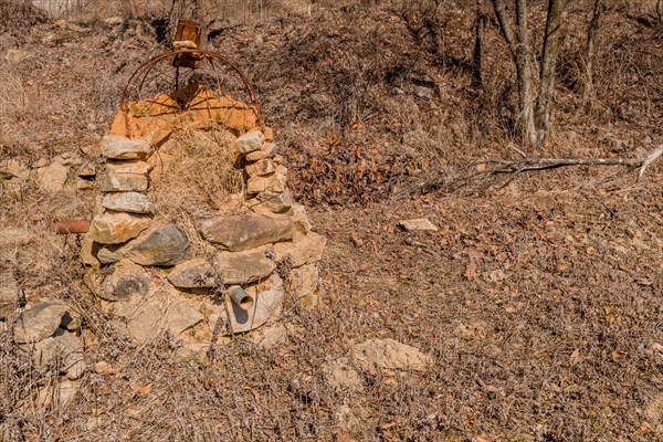 Stone structure with rusted wire frame and pipe sticking out of bottom in mountain park in Boeun, South Korea, Asia